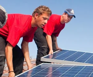 technicians installing solar panels on a roof